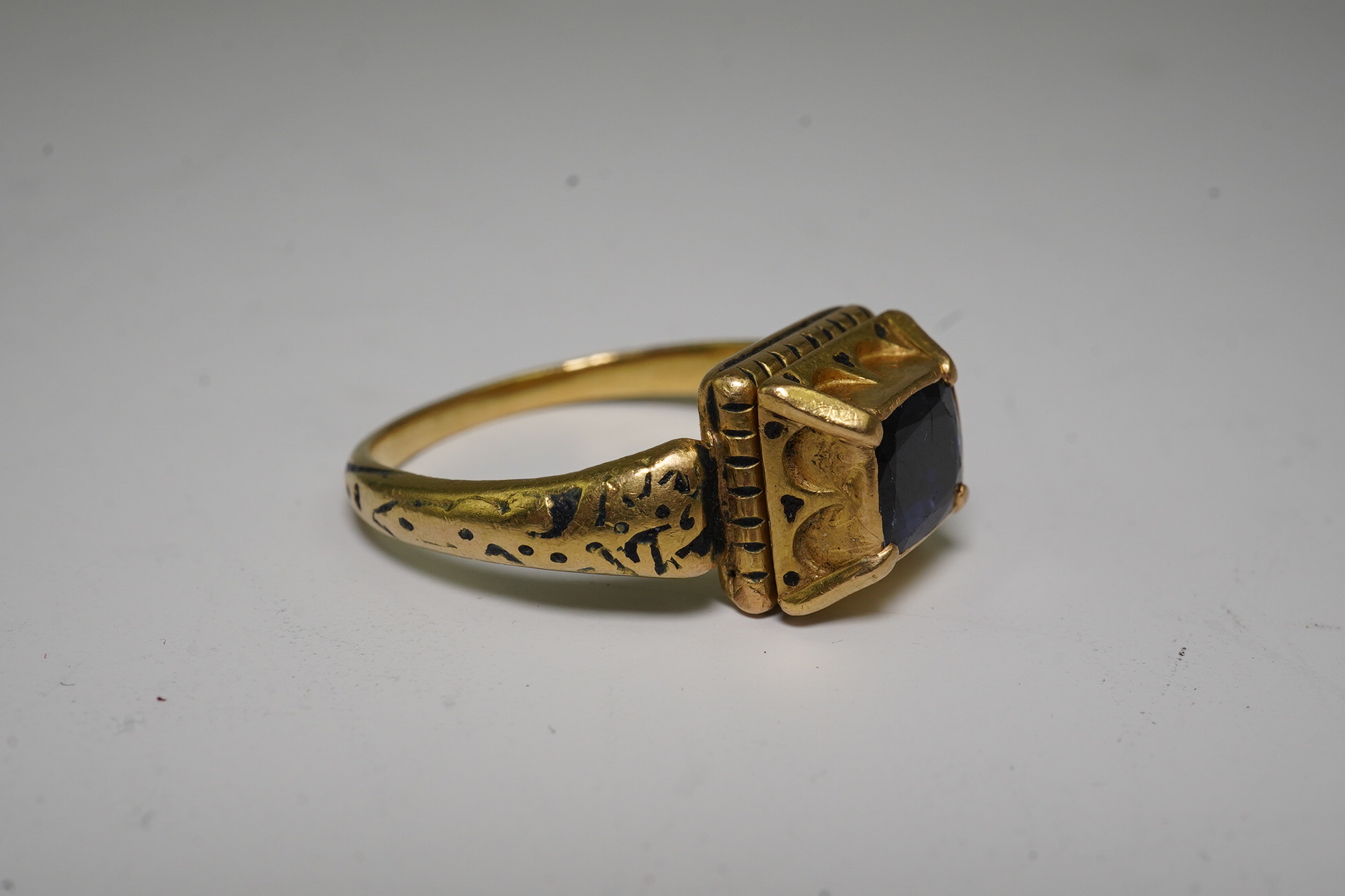 An antique high carat gold, black enamel and collet set cushion cut sapphire set 'poison' ring